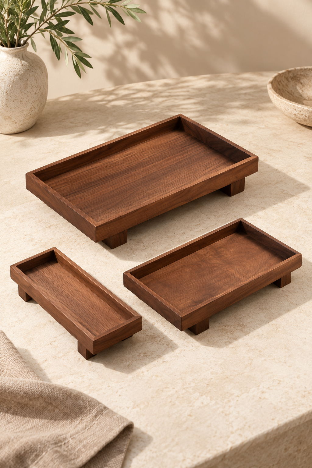 The wooden tray in three sizes, small, medium and large, laid out on a pale stone counter.