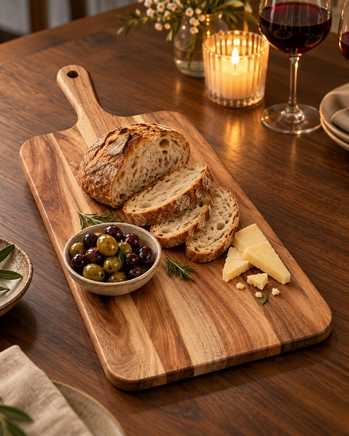 Acacia serving board with bread and olives on a candlelit dinner table. Food not included.
