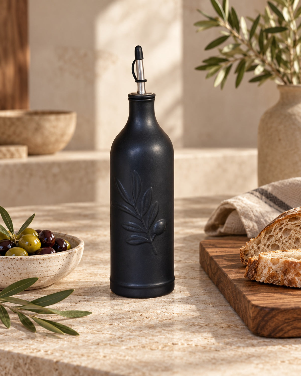 Black ceramic oil bottle with olives and bread on a stone worktop. Food not included.