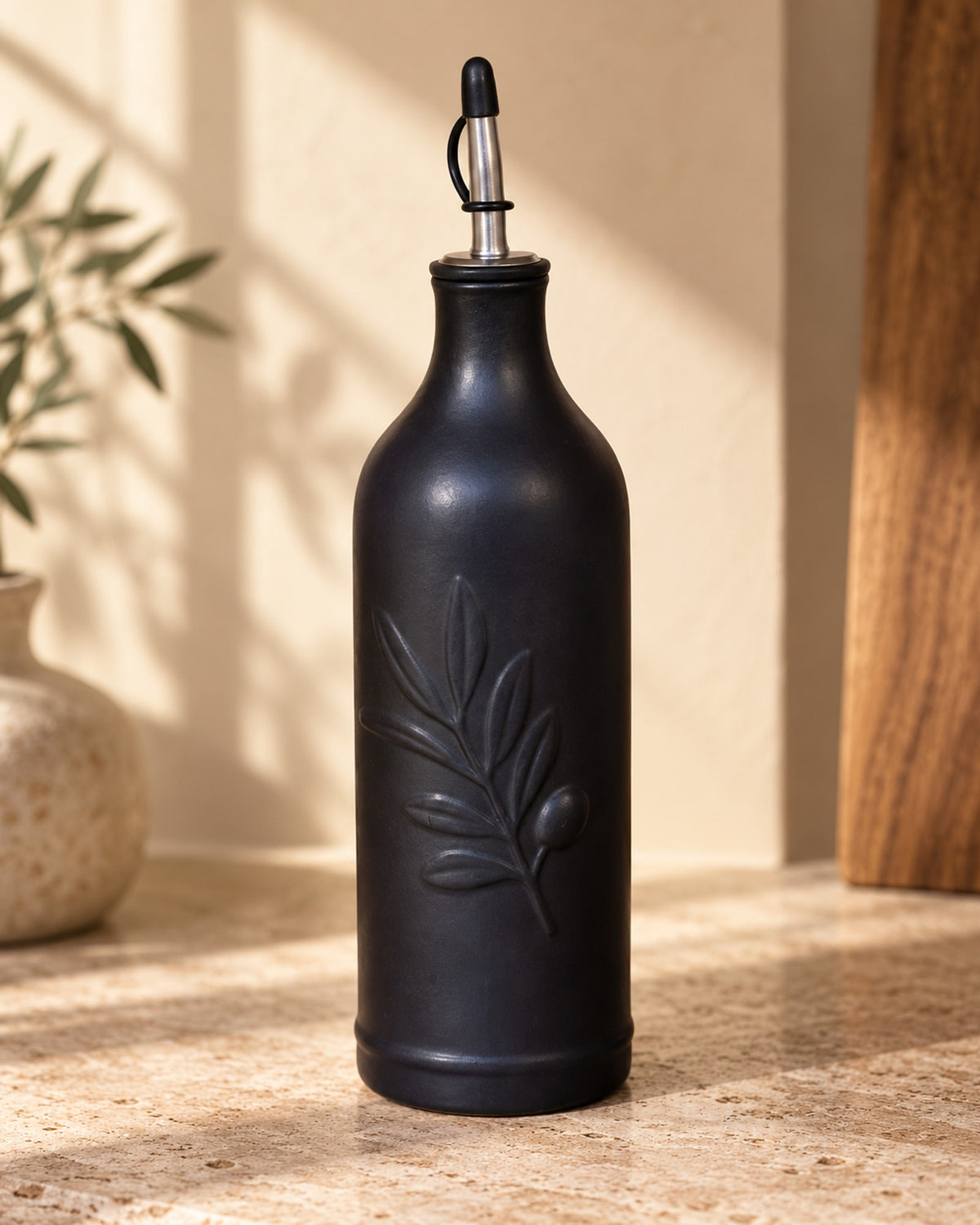 Close-up of the embossed olive branch and pourer on the black bottle.