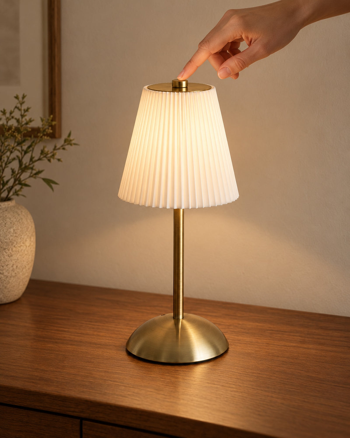 Fingertip touching the top of the cordless lamp to dim it.