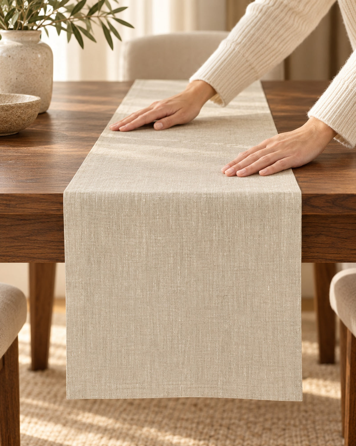 Hands smoothing the linen table runner flat on a table.