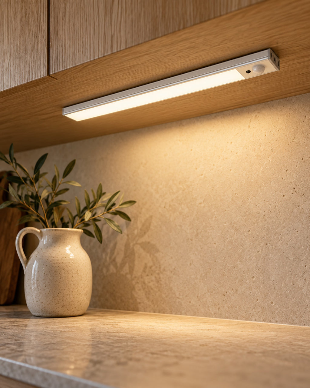 Cabinet light mounted under a wooden kitchen cabinet, casting warm light on the worktop
