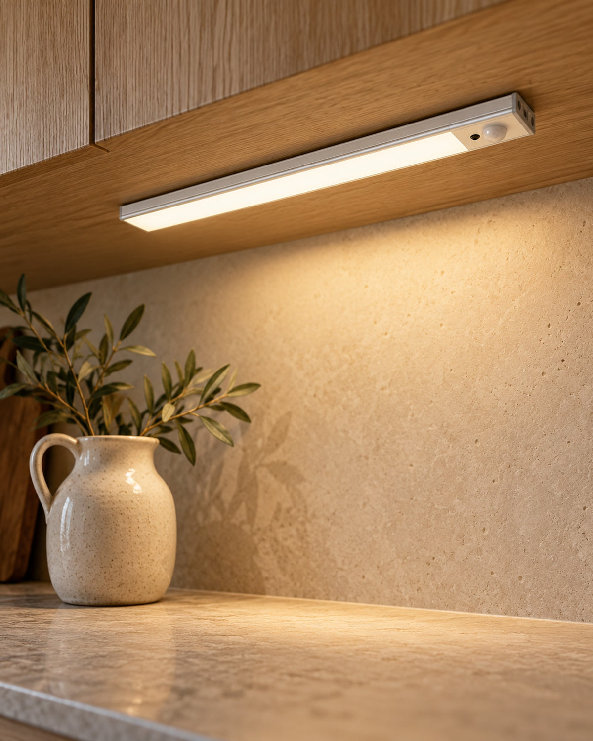 Cabinet light mounted under a wooden kitchen cabinet, casting warm light on the worktop