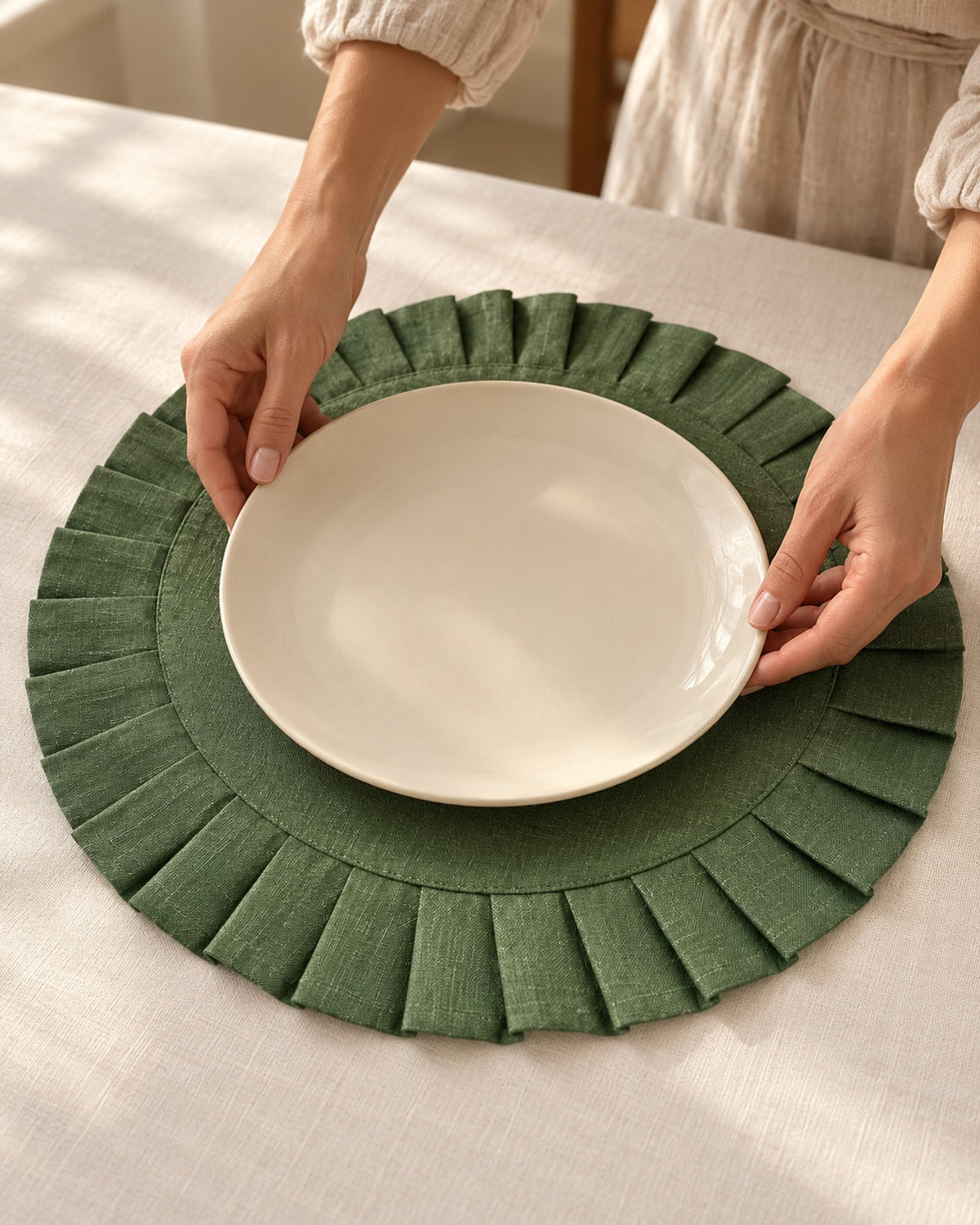Hands placing a cream plate on a green linen placemat.