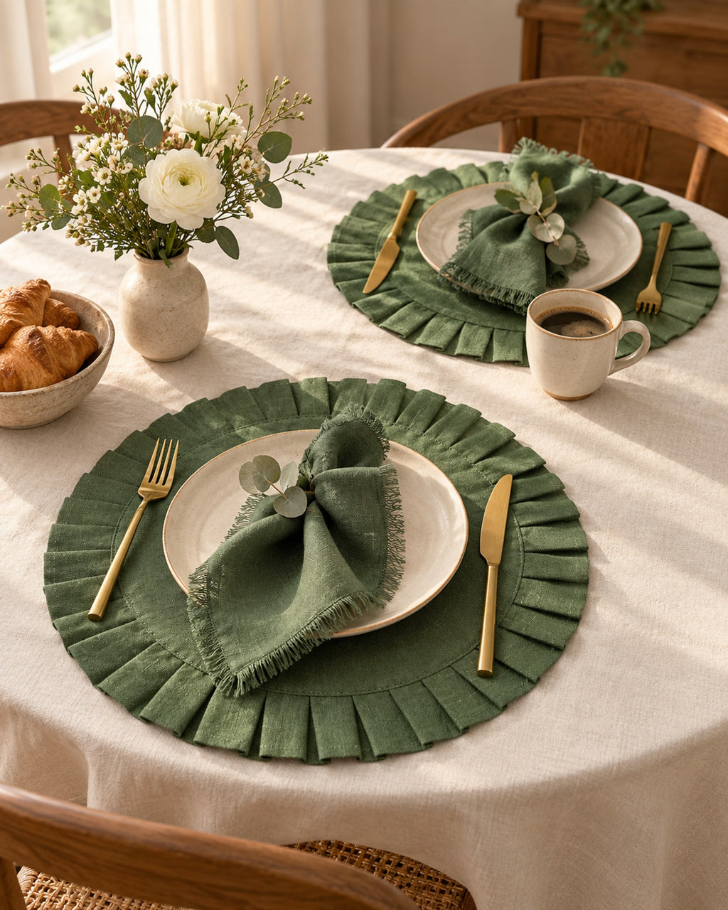 Breakfast table for two with green linen placemats and coffee cups.