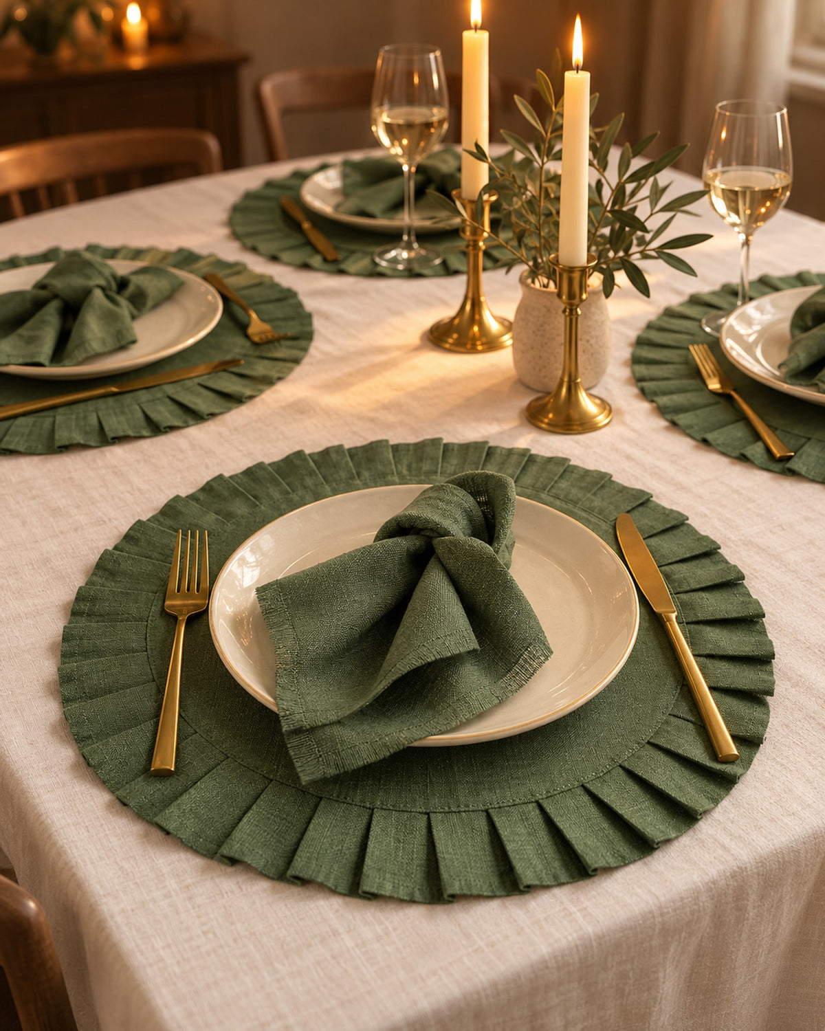 Candlelit dinner table with green linen placemats and brass candle holders.