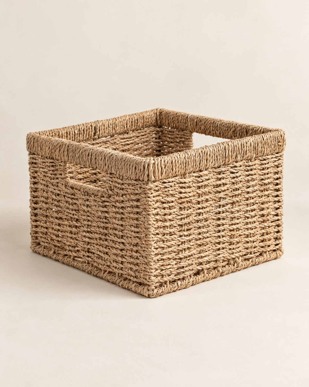 Empty square seagrass basket on a warm off-white surface.