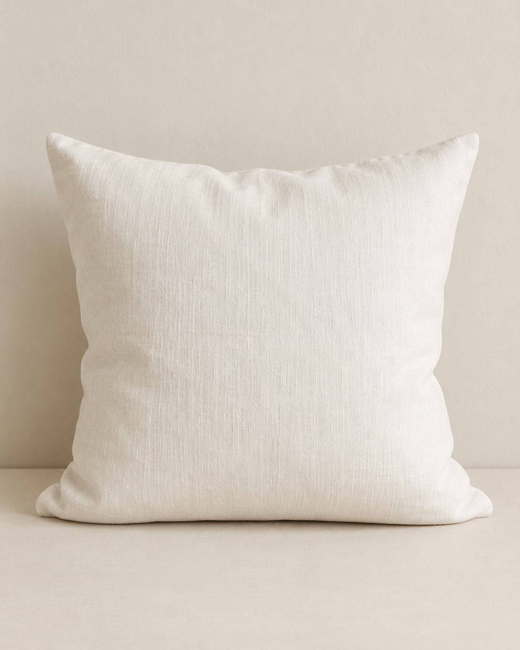 Off-white stonewashed linen cushion against a warm off-white wall. Insert not included.