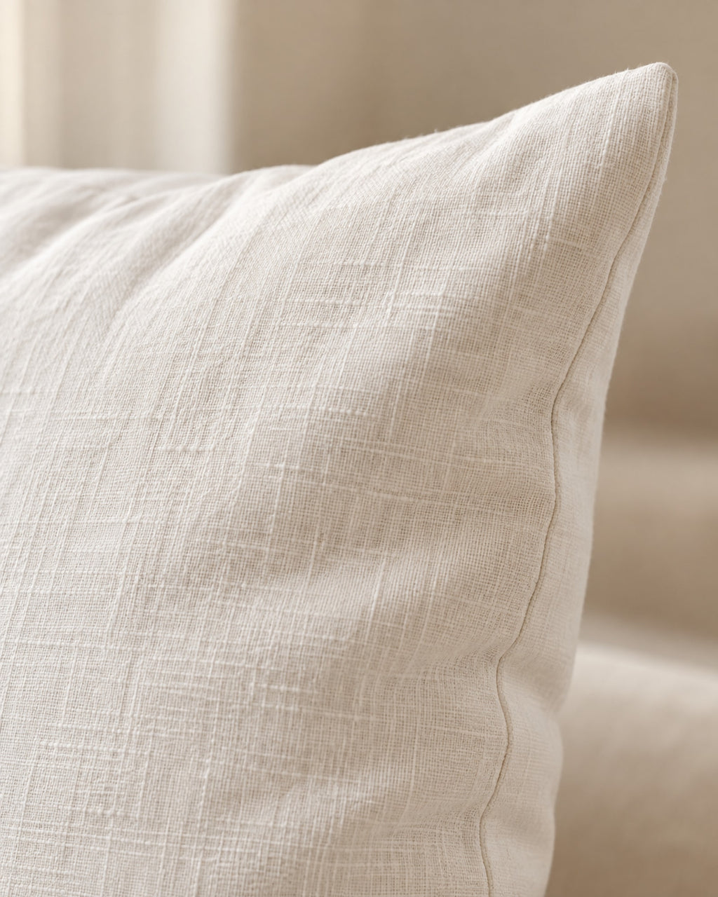 Close-up of the washed linen texture and seam of the cushion cover.