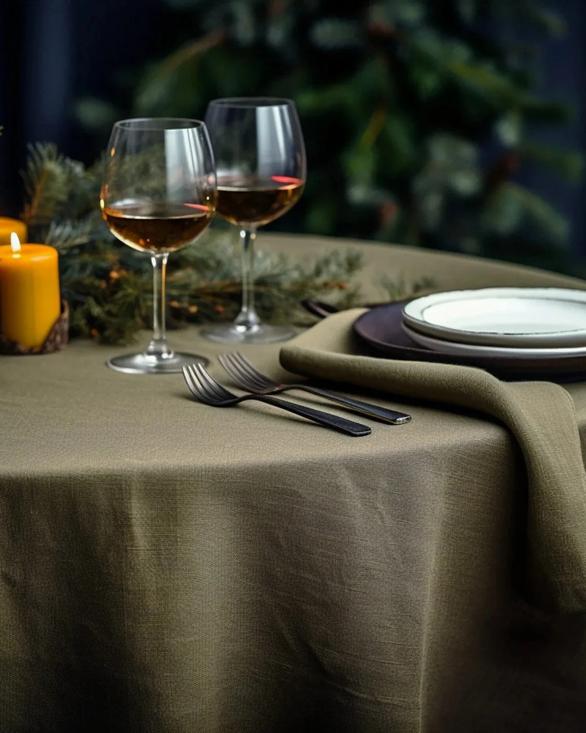 Olive green stonewashed linen tablecloth on a round table with wine glasses (supplier photo)