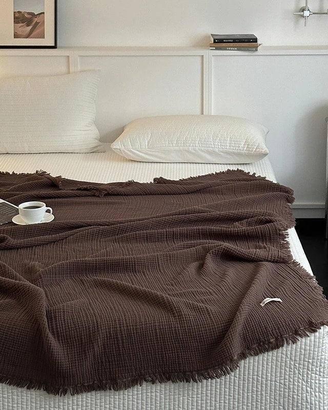 Waffle cotton throw in dark chocolate brown with fringe, spread over a bed (supplier photo)