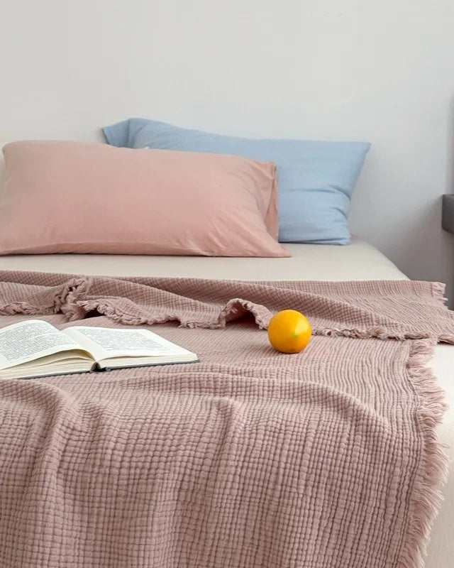 Waffle cotton throw in dusty rose with fringe, spread over a bed (supplier photo)