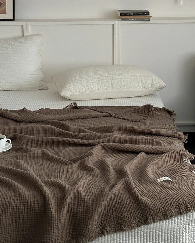 Waffle cotton throw in taupe with fringe, spread over a bed (supplier photo)
