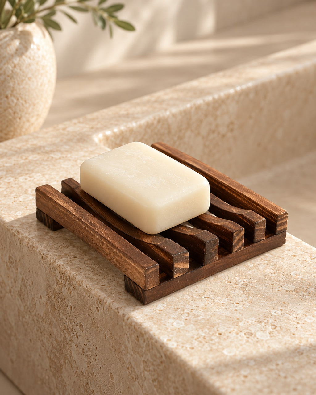 Wooden soap dish with soap on a stone bathroom basin. Soap not included.