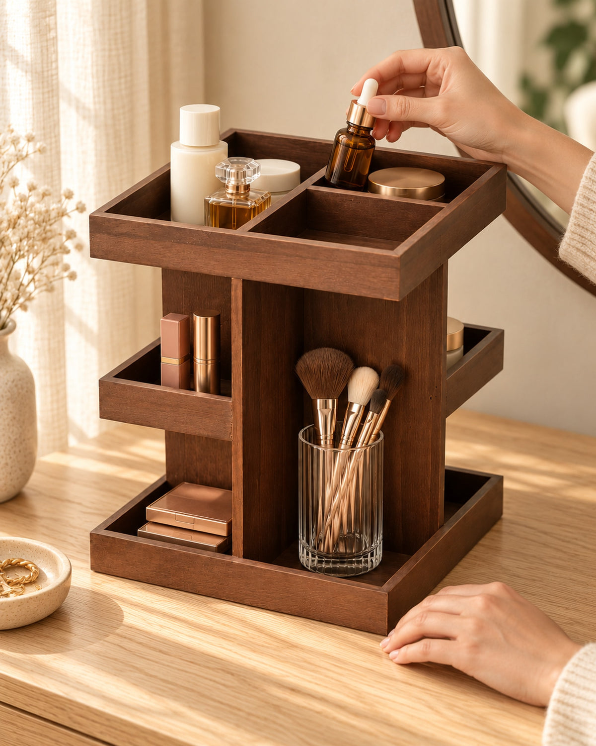 Hands placing a serum bottle in the wooden organiser, filled with skincare, lipsticks and make-up brushes on a dressing table. Accessories not included.